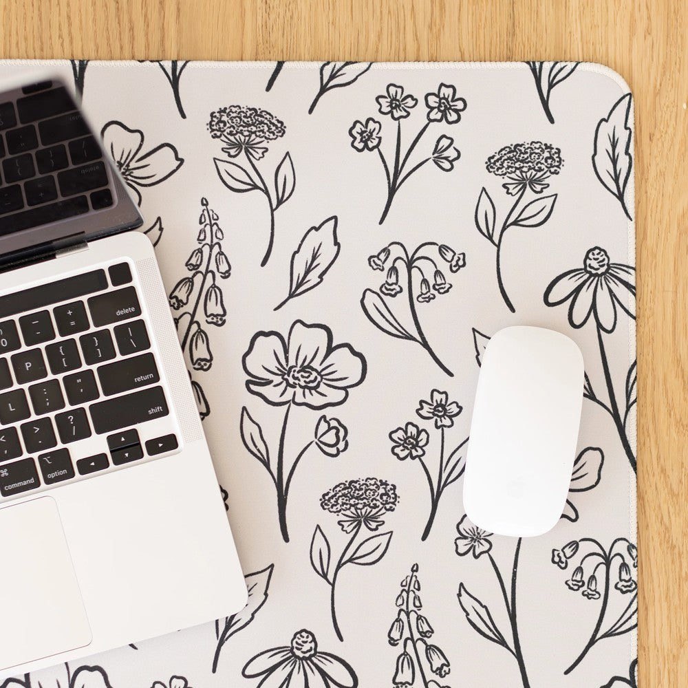 Laptop and mouse on floral-patterned desk mat.