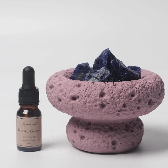 Purple stone holder with blue crystals and fragrance oil bottle.