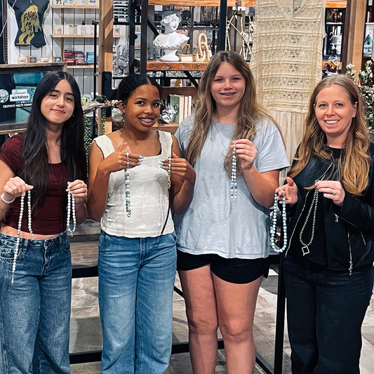 Four jewelry workshop participants holding their creations