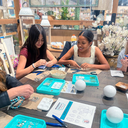 Jewelry workshop participants smiling and working around a group table