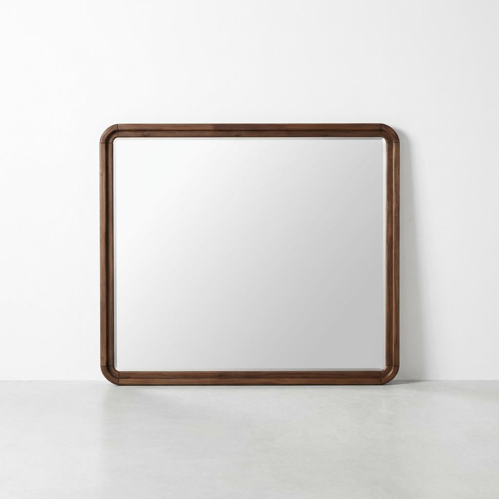 Square mirror with a dark wooden frame on a white wall.