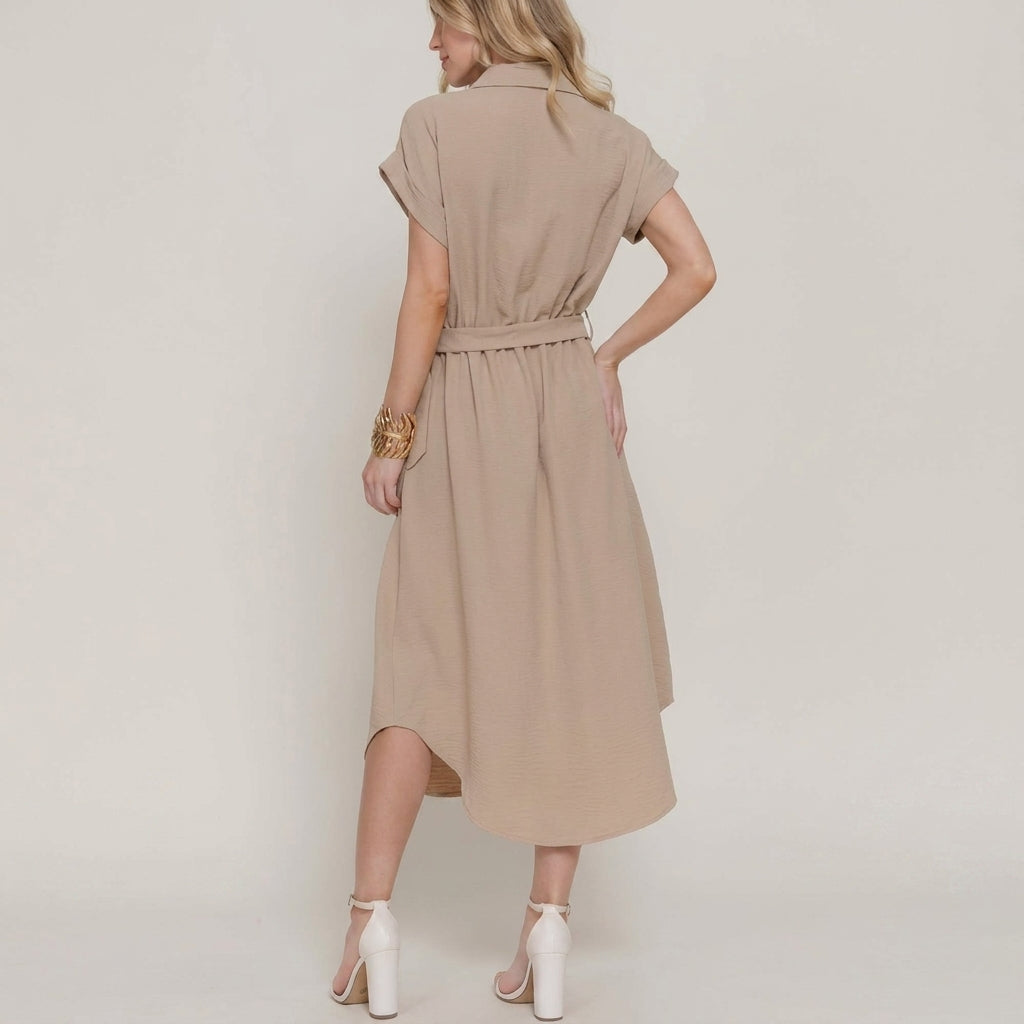 Woman in beige dress and heels, standing sideways.