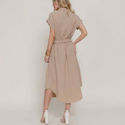 Woman in beige dress and heels, standing sideways.