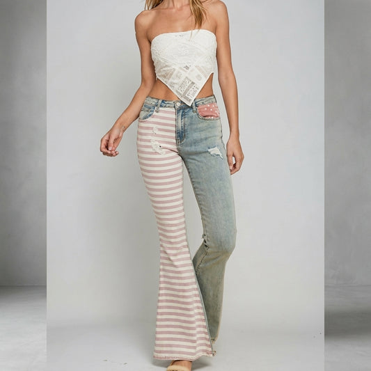 Model in a strapless top and mismatched jeans poses in a studio setting.