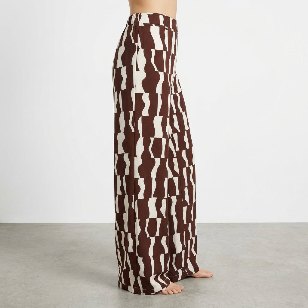 Brown and white patterned wide-leg pants on person, with a plain background.