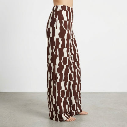 Brown and white patterned wide-leg pants on person, with a plain background.