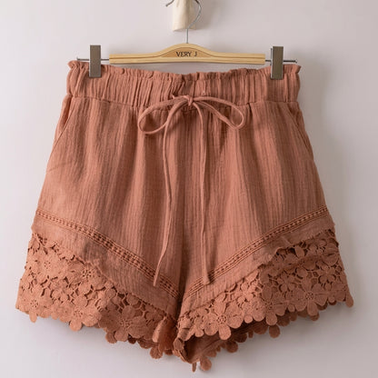 Brown shorts with decorative lace hem on a hanger.
