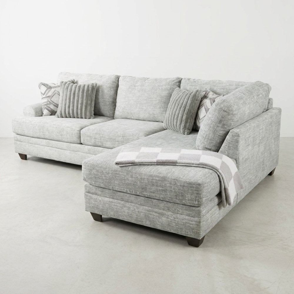 Gray sectional sofa with cushions and a checkered throw blanket.
