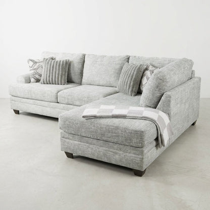 Gray sectional sofa with cushions and a checkered throw blanket.