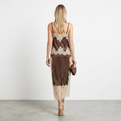 Woman in lace-trimmed brown dress, holding a clutch, viewed from behind.