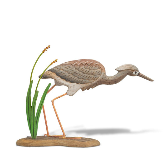Wooden heron sculpture with green reeds on a base.
