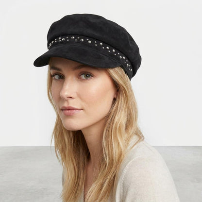 Woman in a studded black cap and beige sweater.