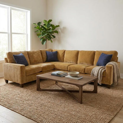 Cozy living room with tan sectional, blue pillows, and wooden coffee table.
