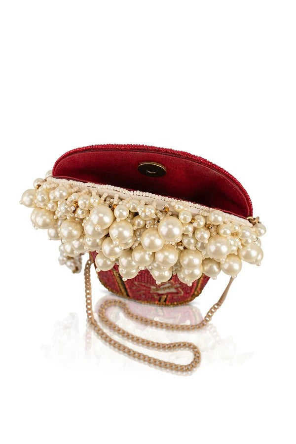 Opulent red clutch adorned with cascading pearls and chain strap.