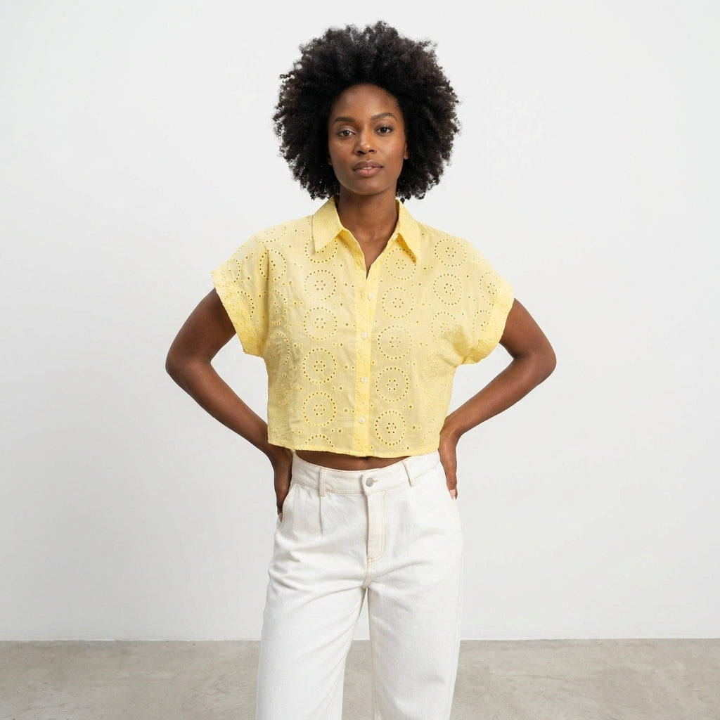 Person in yellow cropped top and white pants standing confidently.