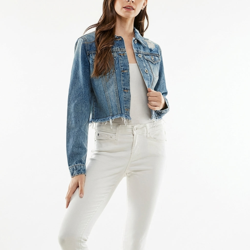 Smiling woman in denim jacket standing outdoors with cafe lights.