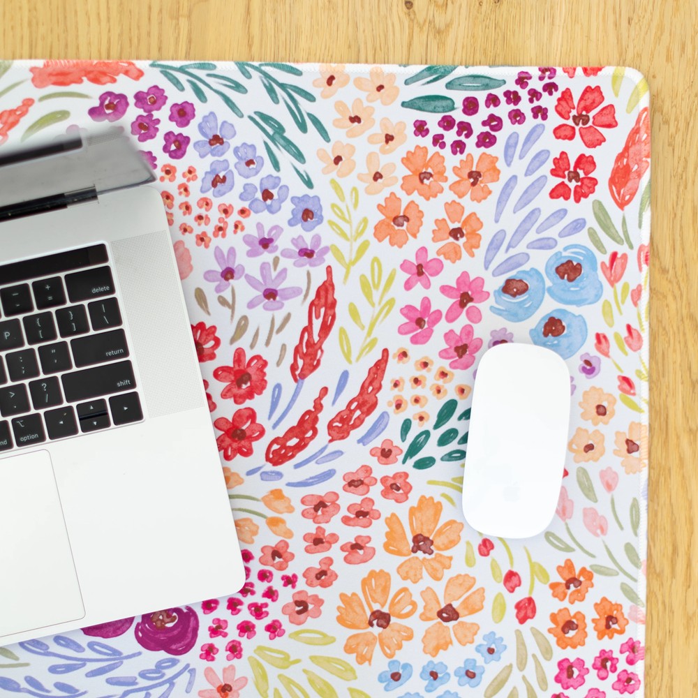 Laptop and mouse on a colorful floral design mat.