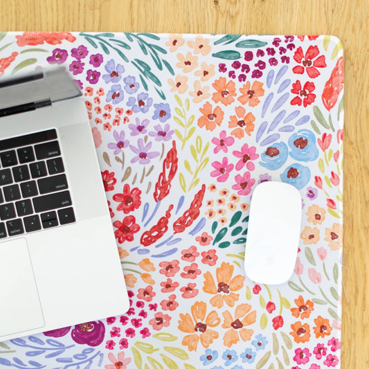 Laptop and mouse on a colorful floral design mat.