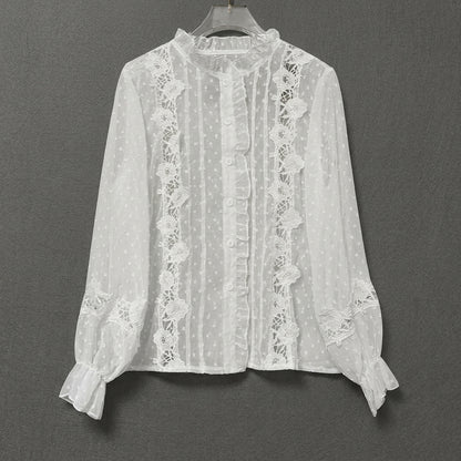 White lace blouse with ruffles and floral details on a hanger.