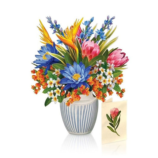 Colorful flower bouquet in striped vase with card nearby.
