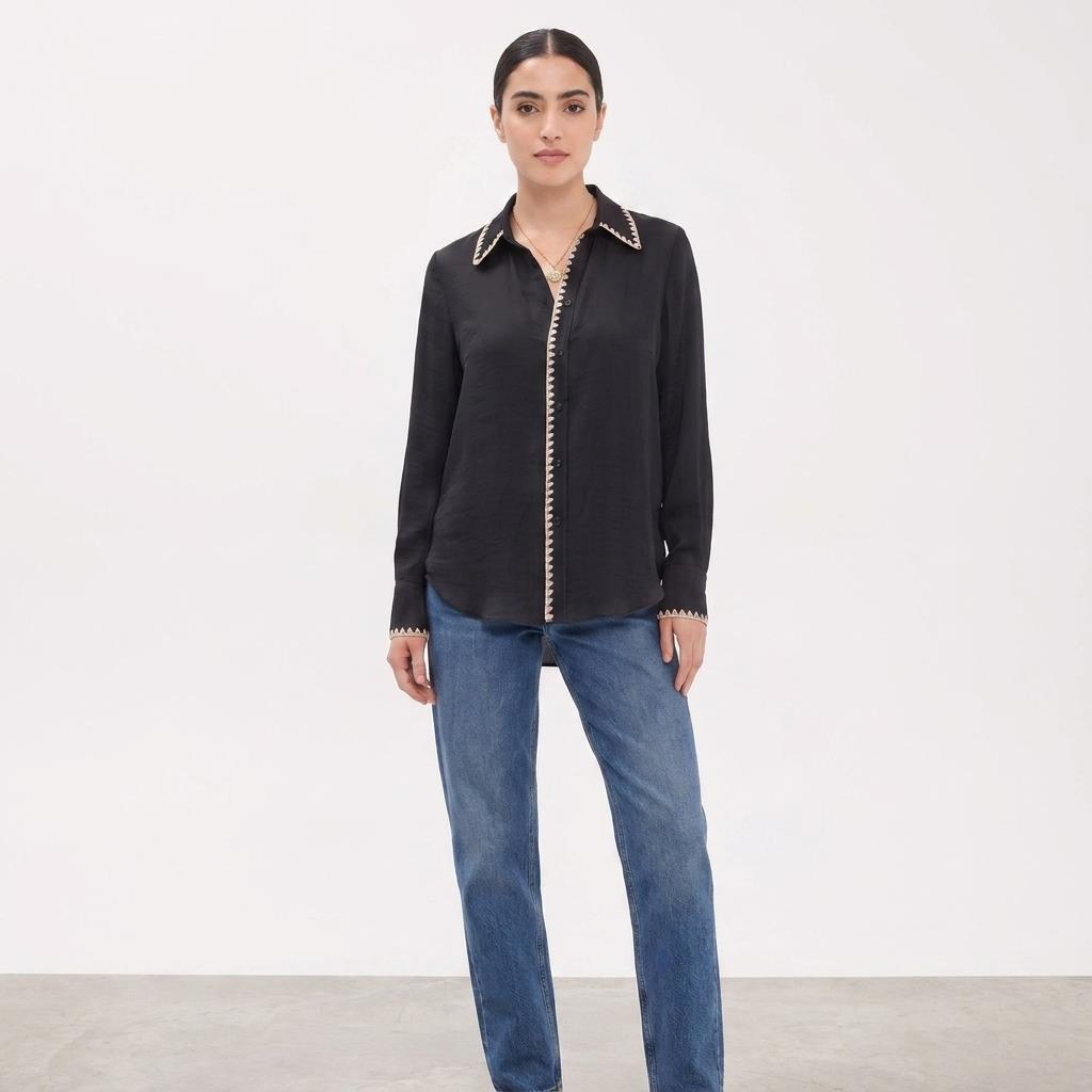 Person in black blouse and jeans on a plain background.