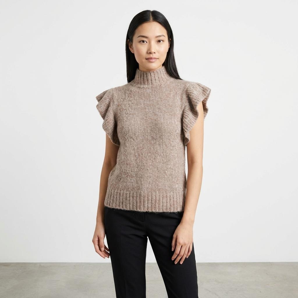 Woman in a brown ruffled sweater and black pants against a white background.