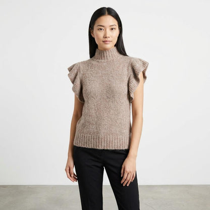 Woman in a brown ruffled sweater and black pants against a white background.