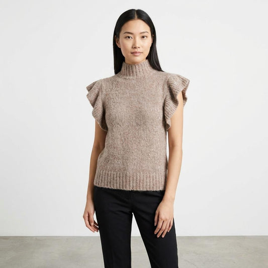 Woman in a brown ruffled sweater and black pants against a white background.
