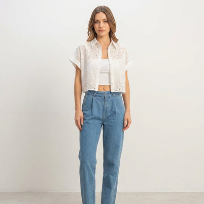 Person in casual outfit: white shirt, crop top, blue jeans, neutral background.