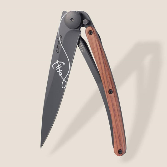 Sleek folding knife with wood handle and engraved blade design.