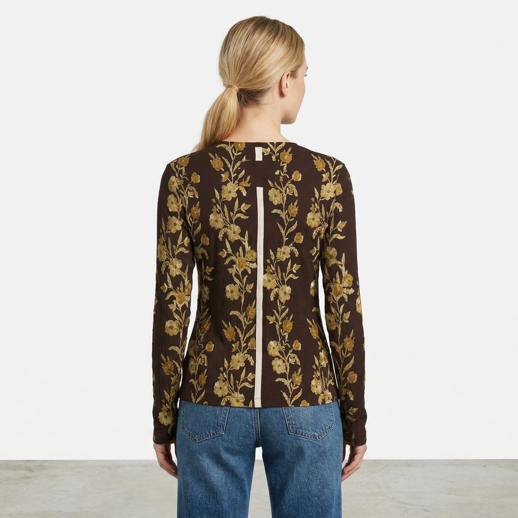 Person in floral top and jeans, hair tied back.