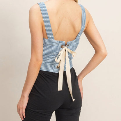 Back view of woman in striped top with tie, wearing black pants.