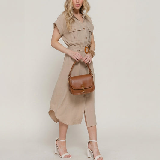 Woman in beige dress holding a brown handbag.