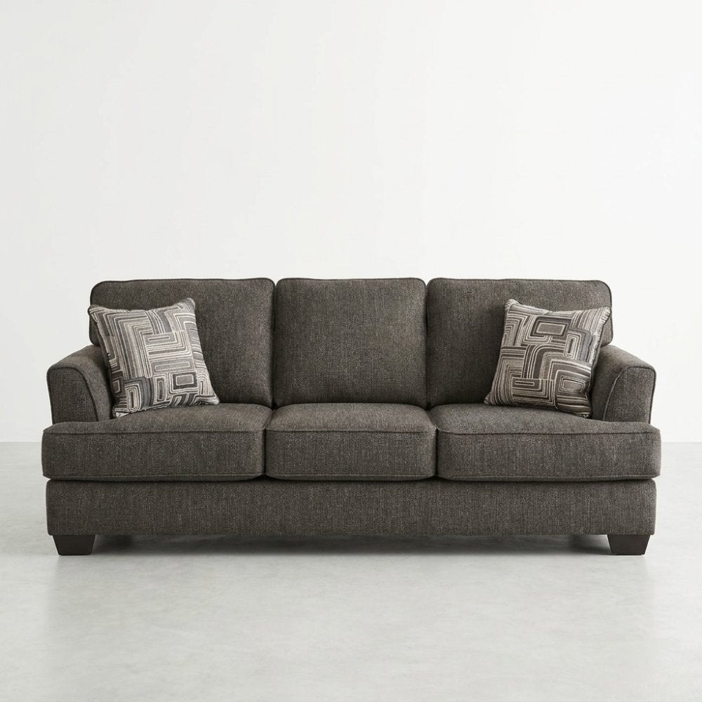 Gray sofa with two patterned cushions in a minimal setting.