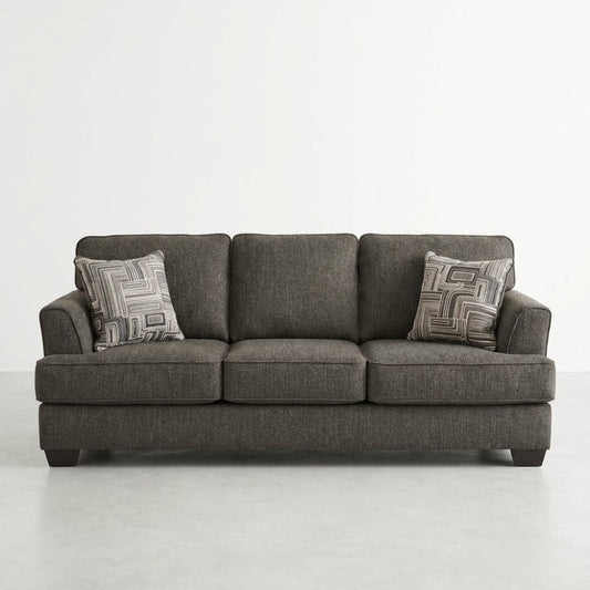 Gray sofa with two patterned cushions in a minimal setting.