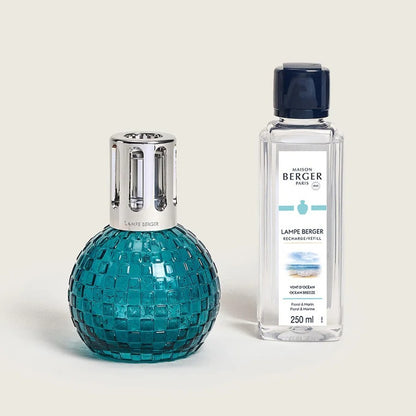 Blue Lampe Berger and refill bottle on a beige background.