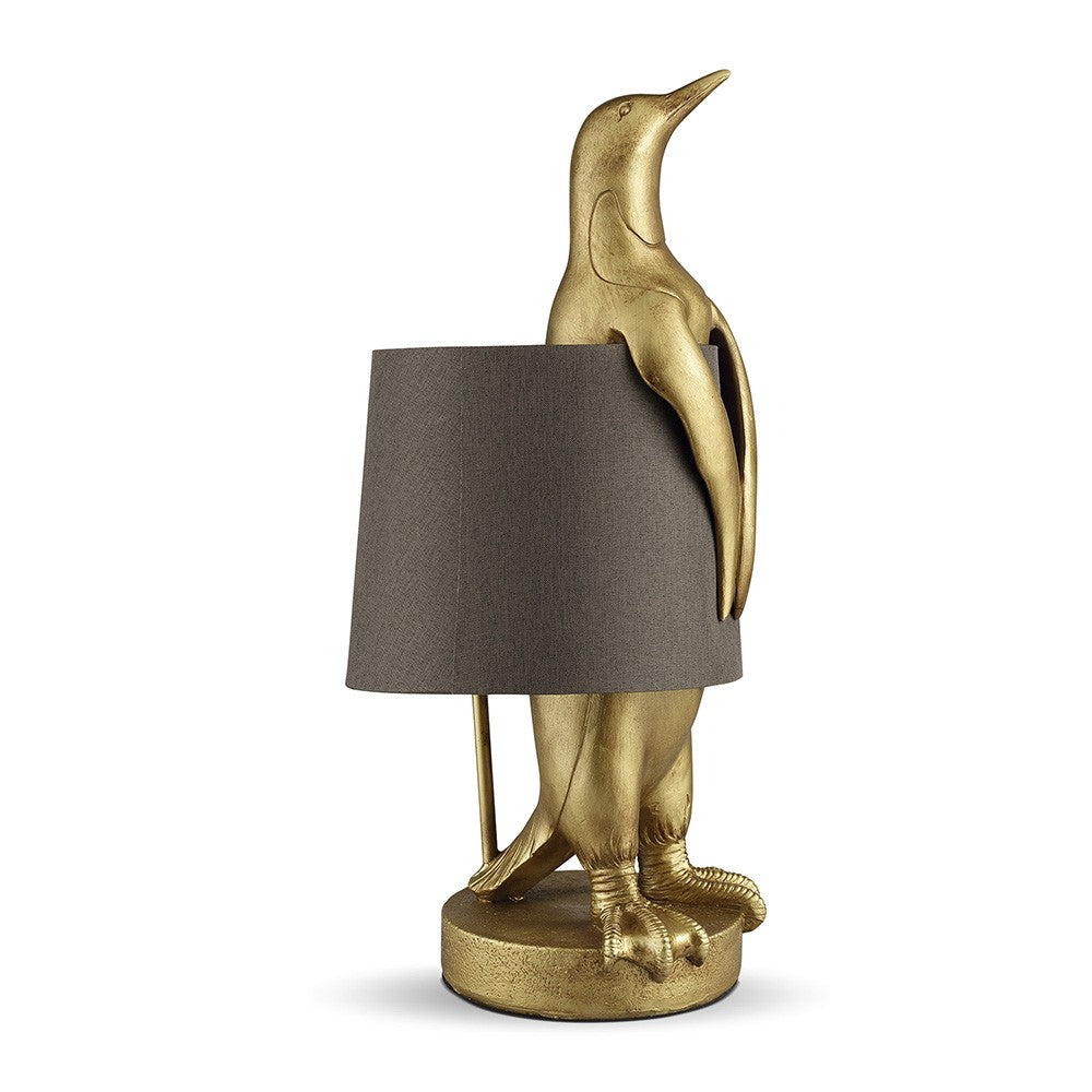 Gold penguin lamp with gray shade.
