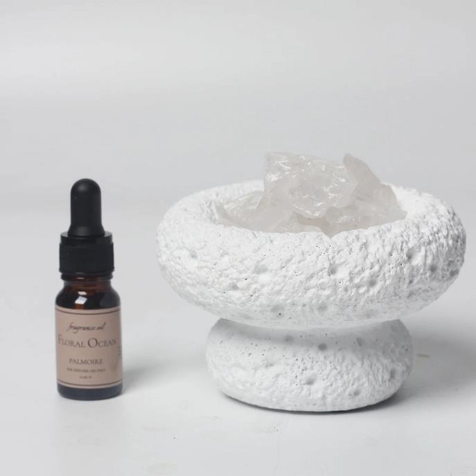 Aromatherapy bottle and textured white dish with crystals.