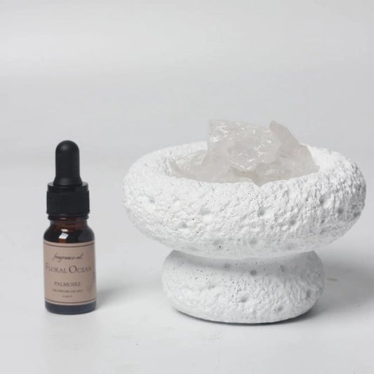 Aromatherapy bottle and textured white dish with crystals.