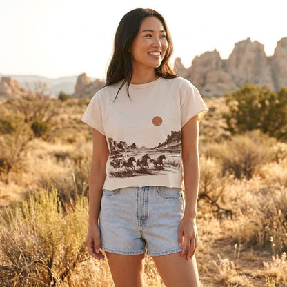 Smiling woman in desert landscape wearing a scenic print shirt.