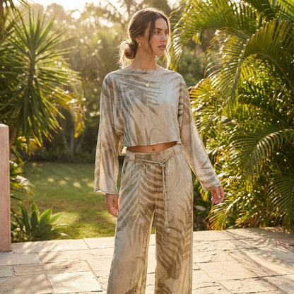 Person in patterned loungewear outside, surrounded by lush greenery.
