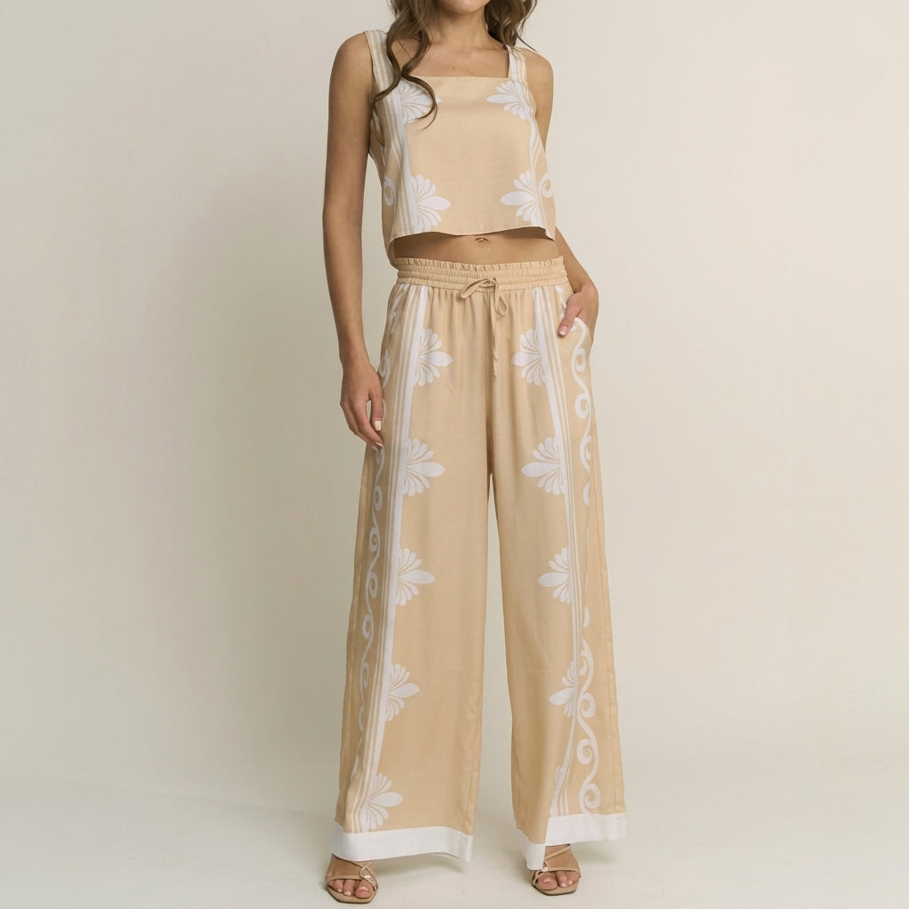 Woman in beige floral-patterned crop top and pants set, standing with hand on hip.