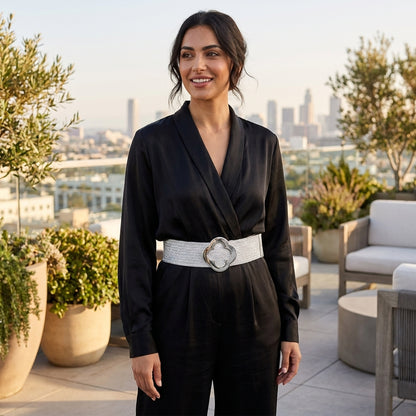 Woman in black outfit with silver belt on a rooftop terrace.