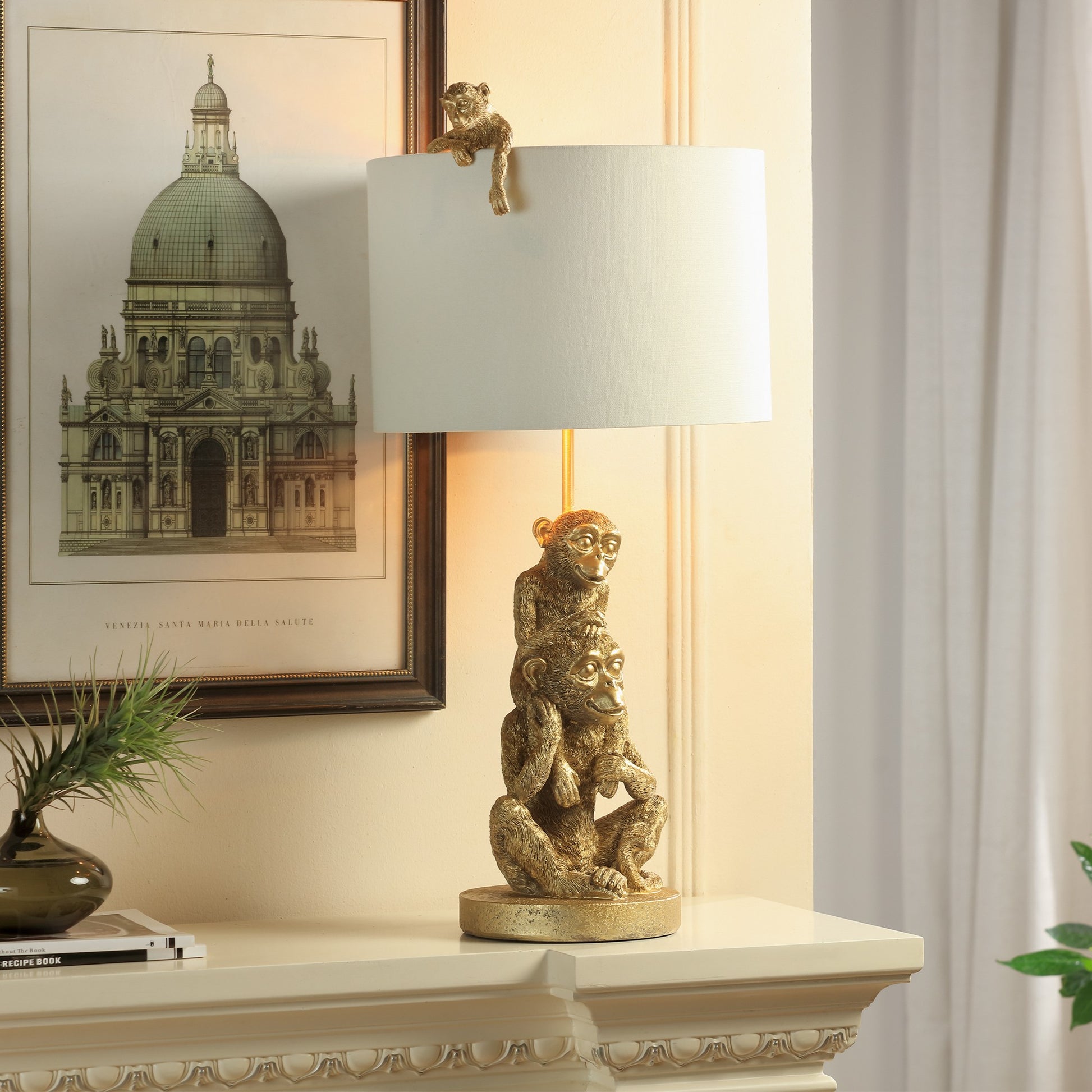 Monkey lamp on a mantel with a framed architecture print.