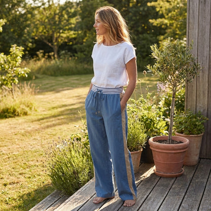 A woman stands on a porch, enjoying a sunny day in a garden.