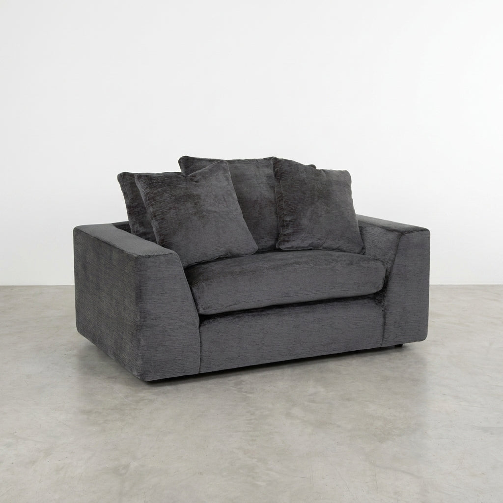 Gray loveseat with plush cushions on a white background.