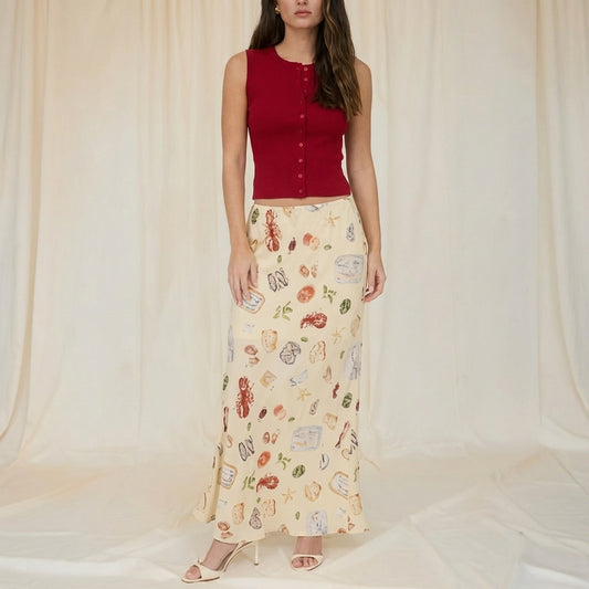 Person in a printed skirt on a terrace by the sea.
