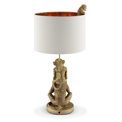 Golden monkey lamp with white shade, one monkey peeking inside.
