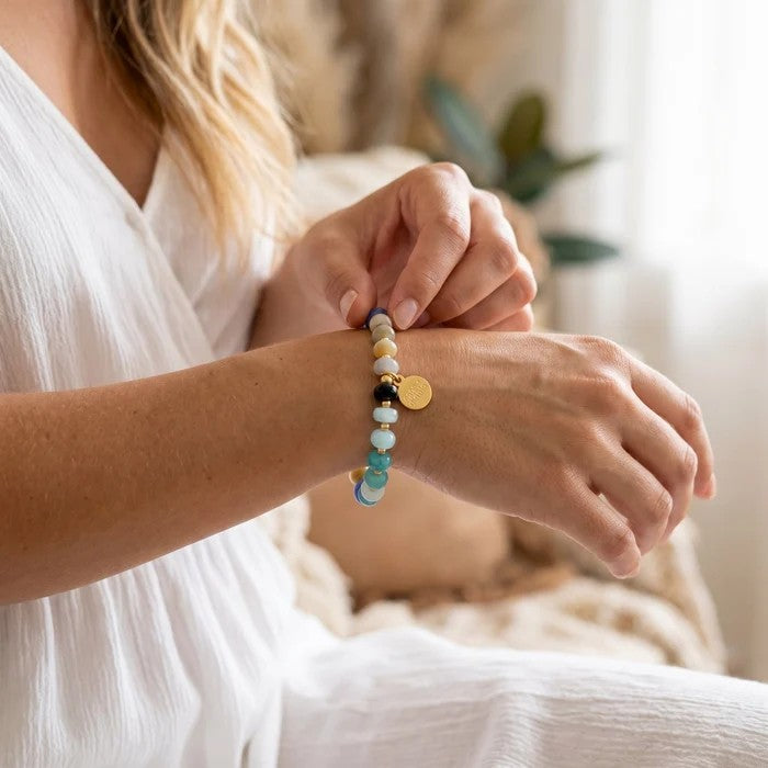 Woman wearing a colorful beaded bracelet with a pendant.