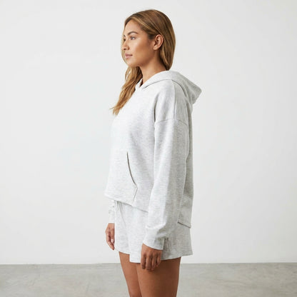 Woman in a gray hoodie and shorts, standing sideways.